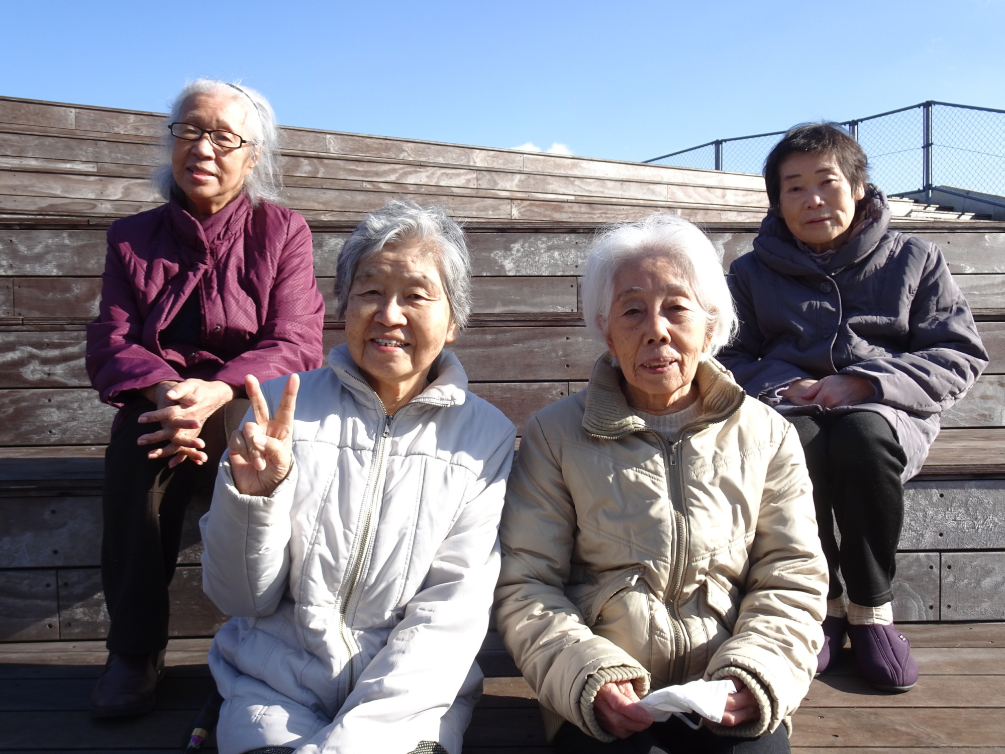 ダム湖を見下ろせる展望デッキの階段に座る利用者さんたち