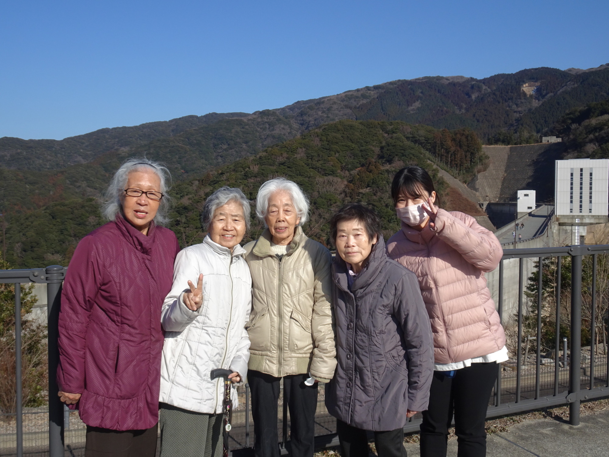 五ケ山ダムで山をバックに写る利用者たちとワーカー