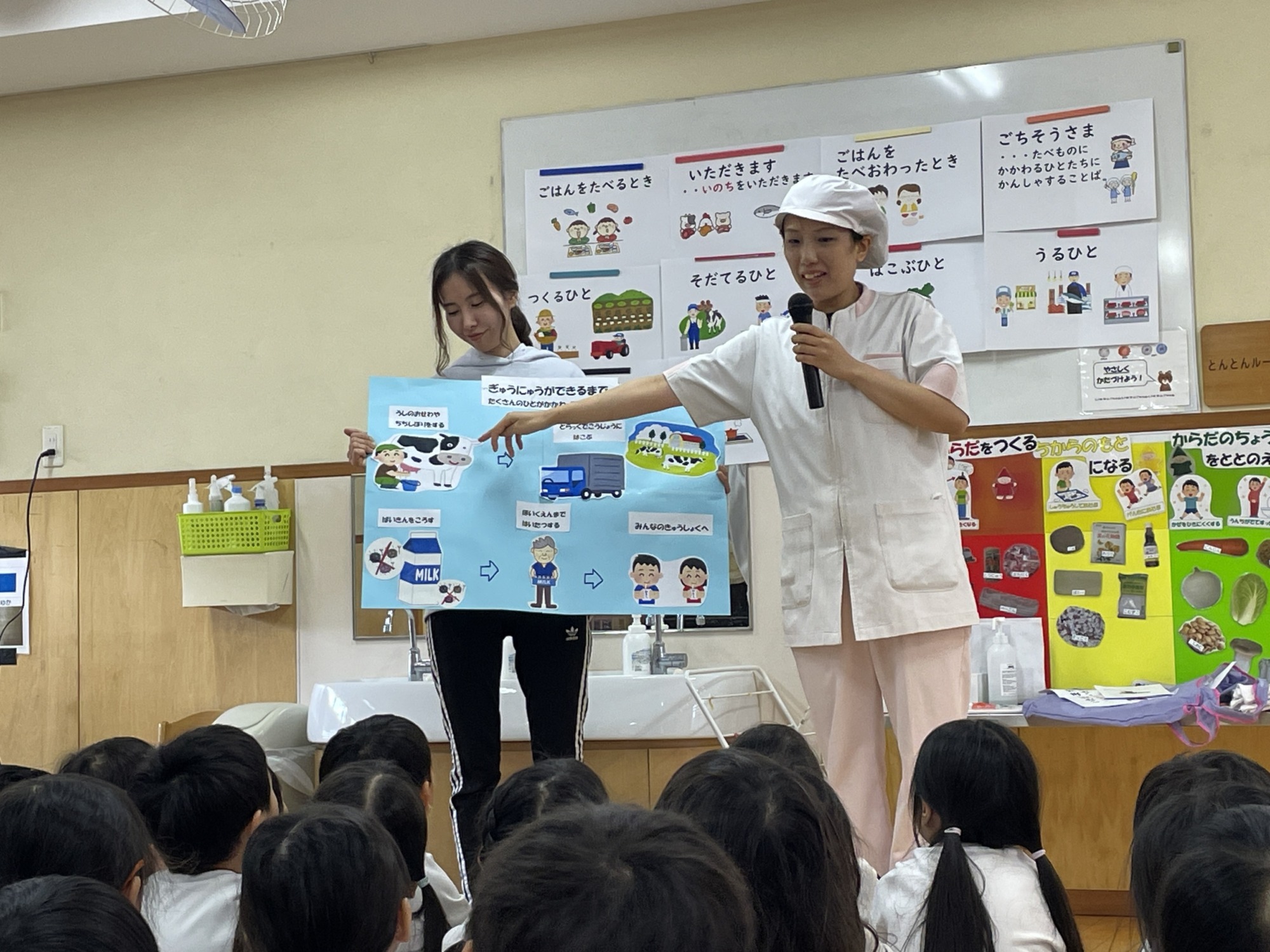 食材がどのようにして食事としてテーブルまで届くかということを保育士と給食職員が子ども達に説明をしています。