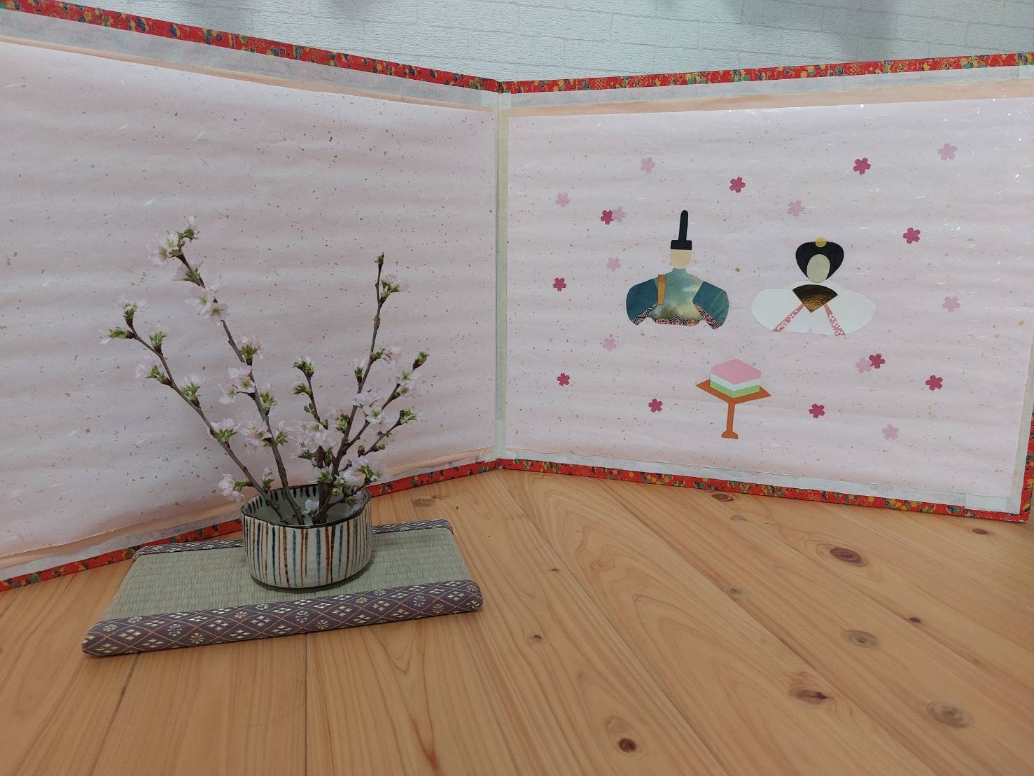 ワーカーの子どもが通う幼稚園の一角にお雛様と早咲きの品種の啓翁桜が飾られている