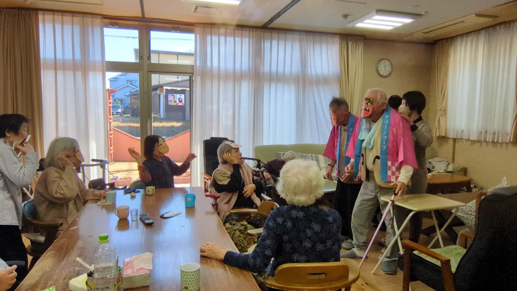 鬼に扮した男性利用者さんたちに豆をなげるおかめのお面をつけた女性利用者さんたち