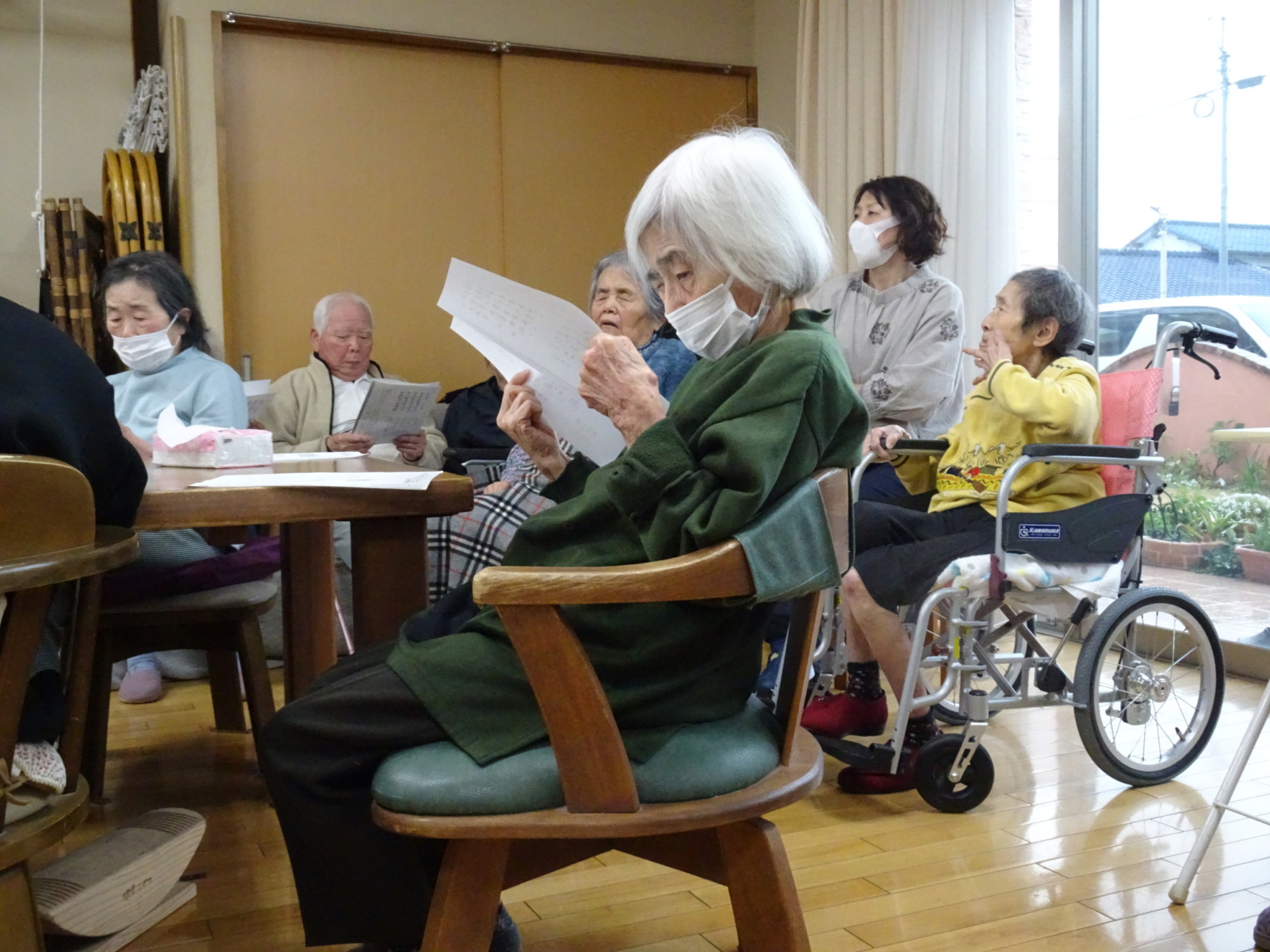 歌詞カードで一生懸命歌詞を目で追う利用者さん