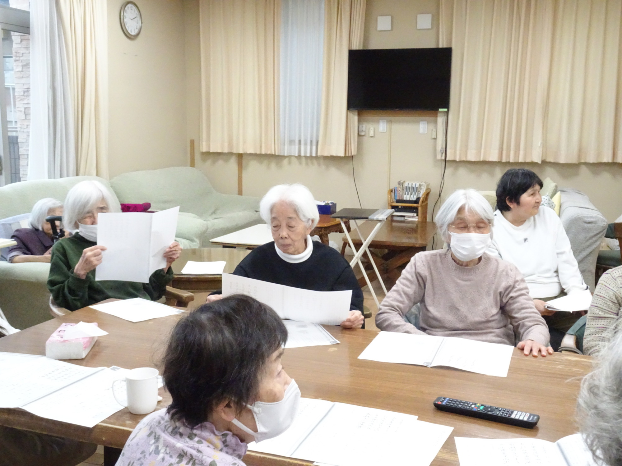 歌詞カードを見ながら一緒に歌う利用者さんたち