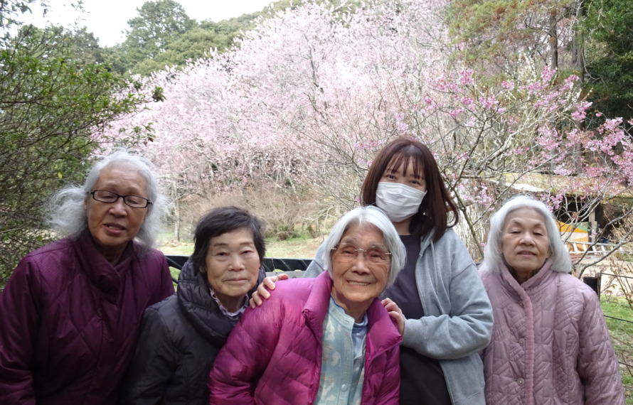 桜の前で撮った利用者さんたちとワーカーの写真