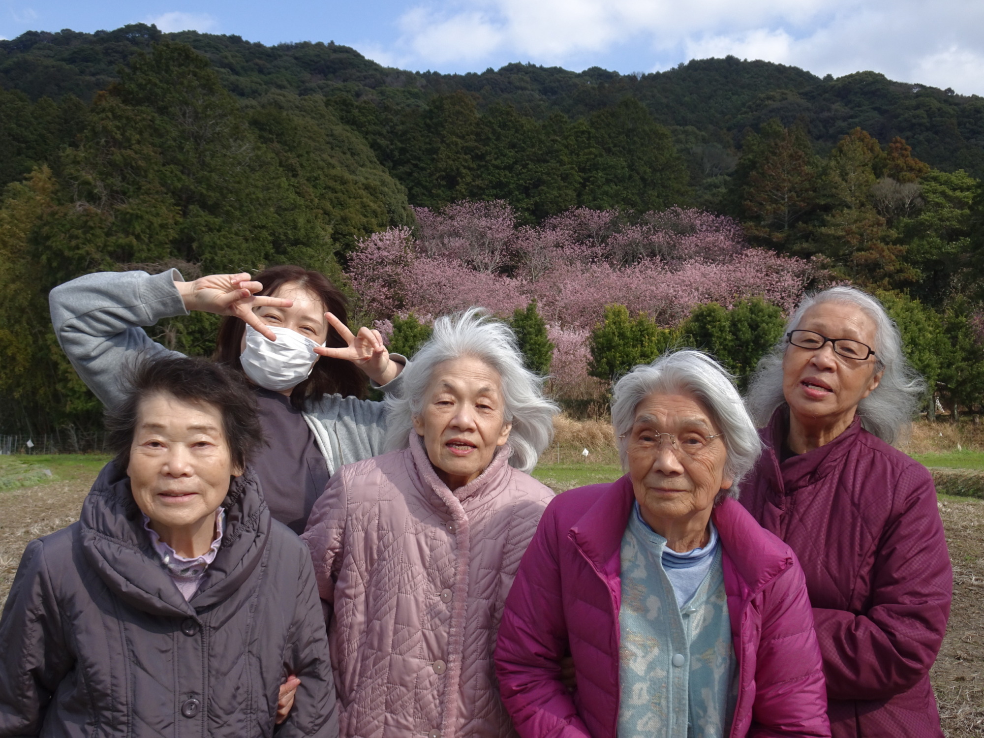 桜の前で撮った利用者さんたちとワーカーの写真