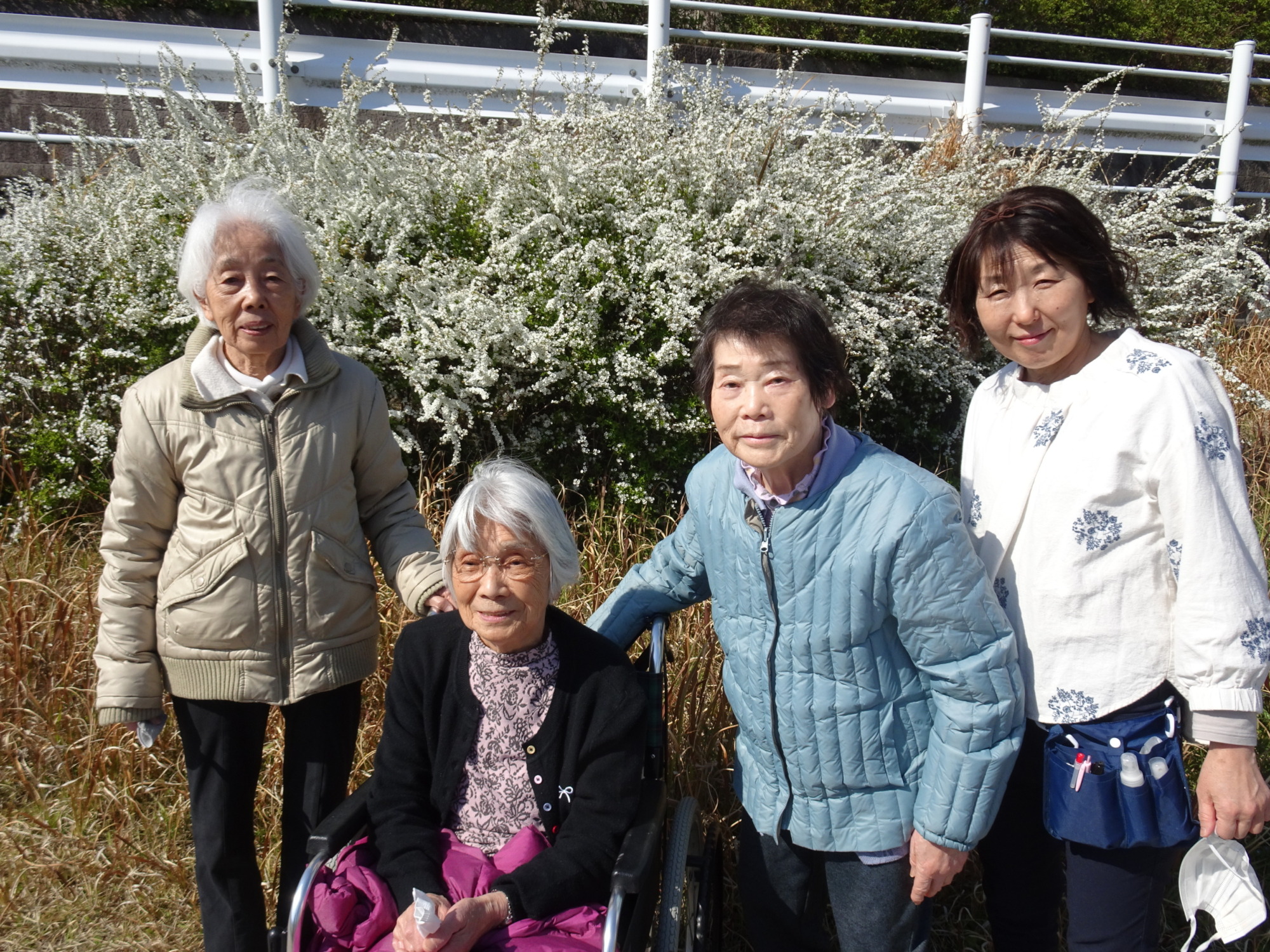 ユキヤナギを一緒に写る利用者さんたちとワーカー