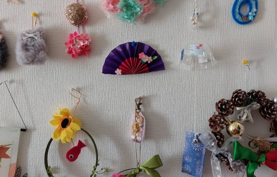 利用者様のお部屋の壁にデイサービスで作られたお花やリース等が飾られている
