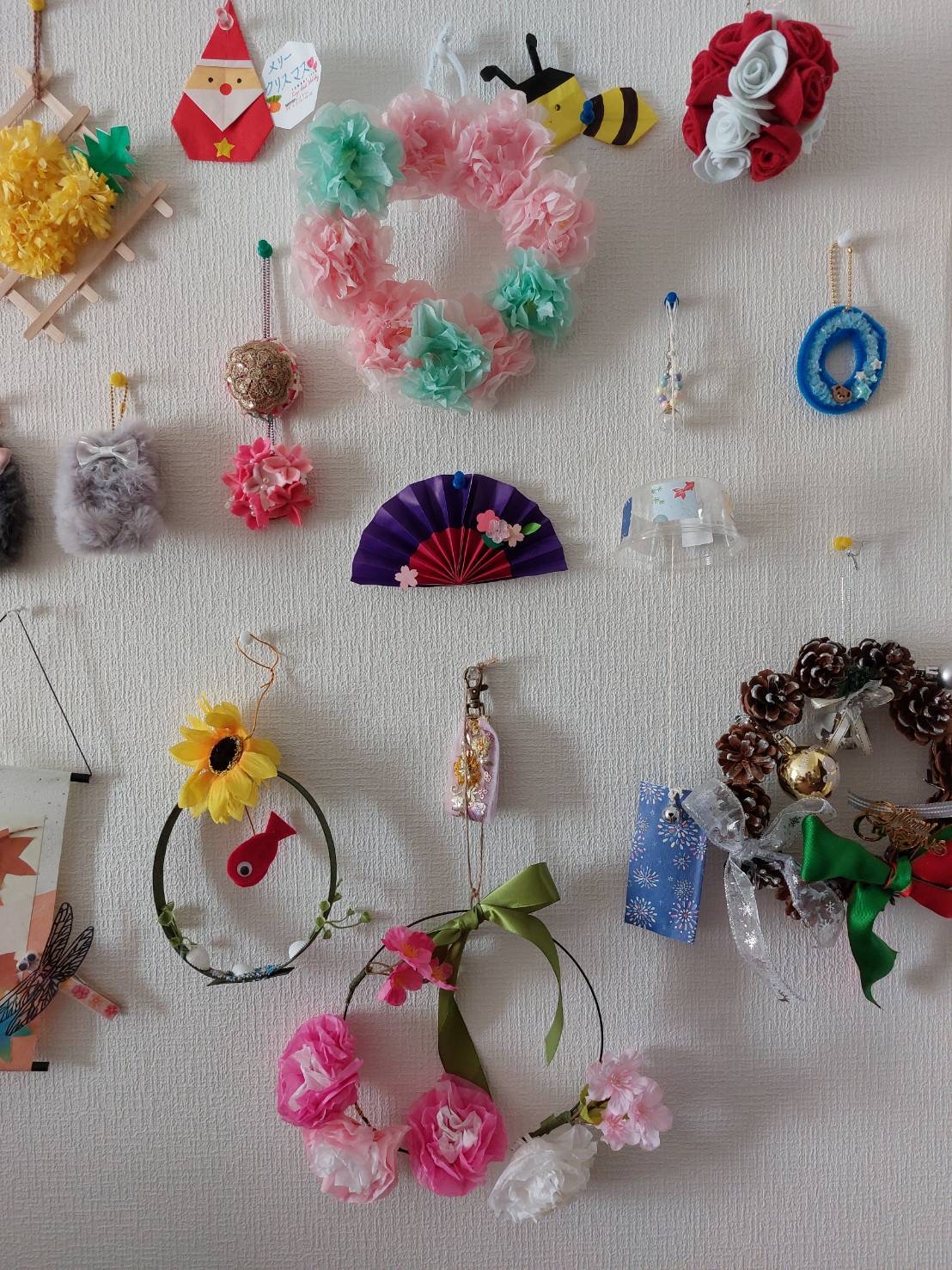 利用者様のお部屋の壁にデイサービスで作られたお花やリース等が飾られている