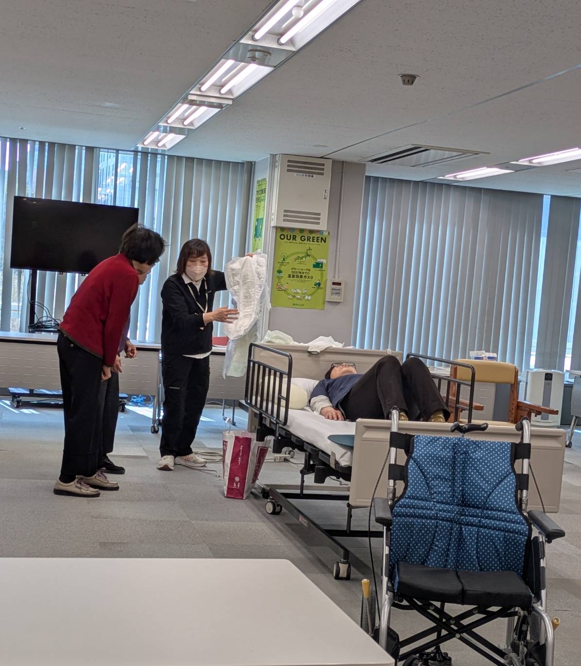 介護教室で講師がおむつやパットを見せながら説明している