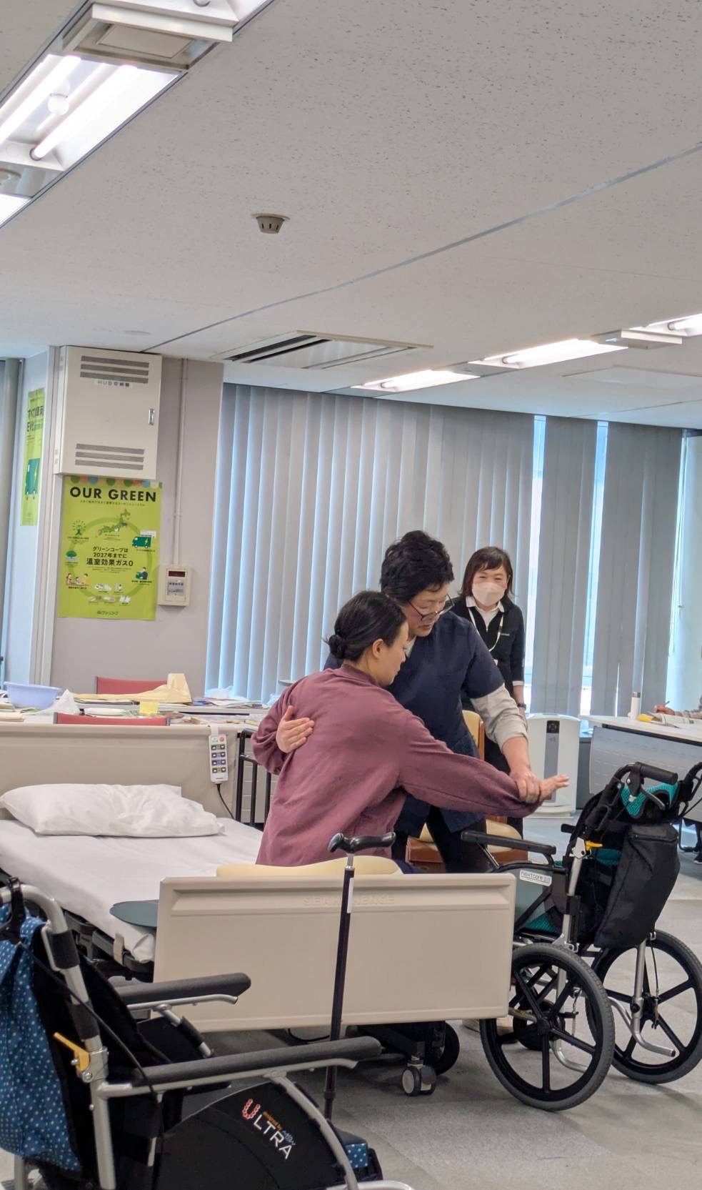 ベッドから車椅子への移乗の仕方を説明しながら実演している