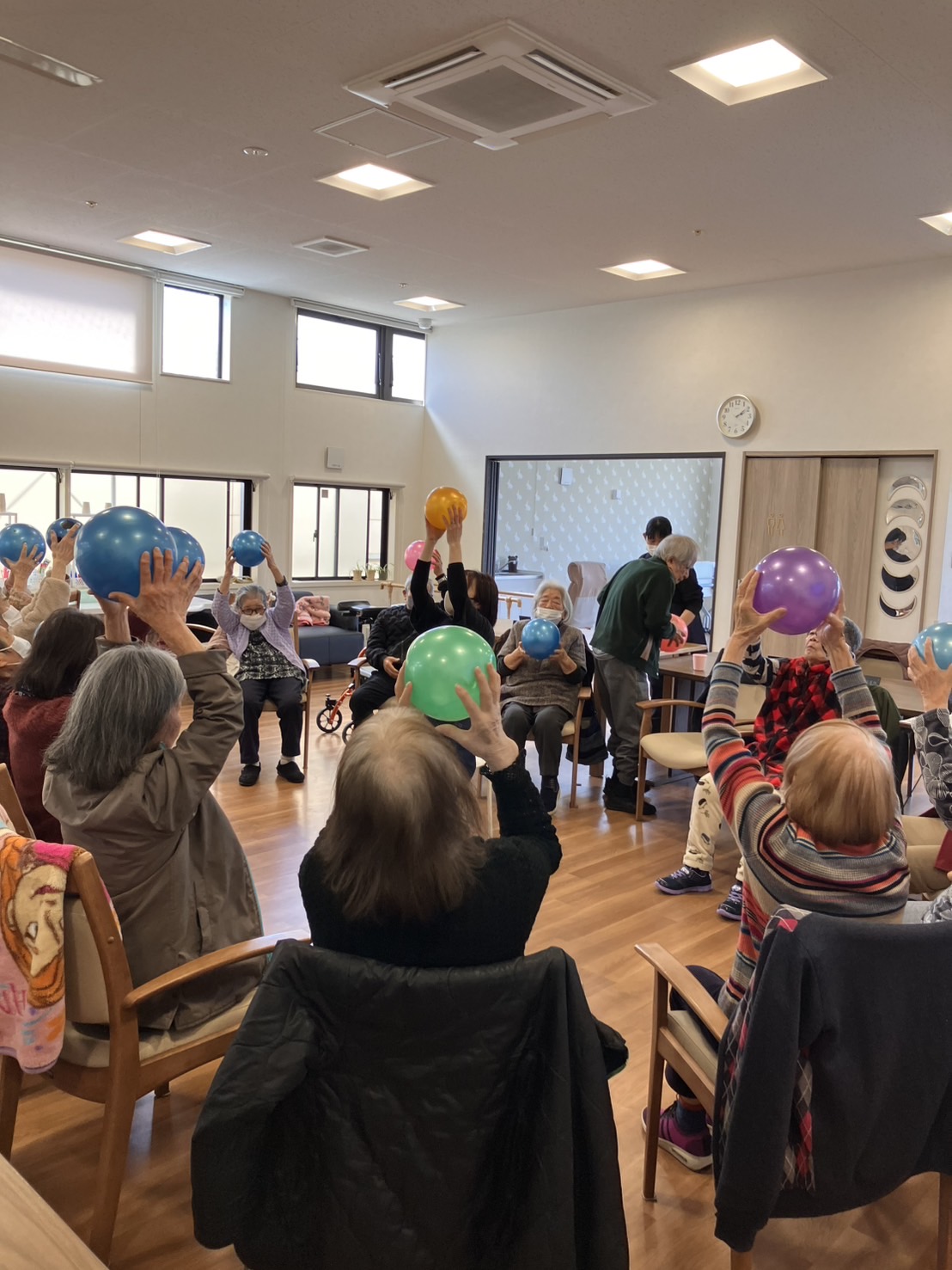 ボールを握ったまま手を上にあげ身体を伸ばす高齢者