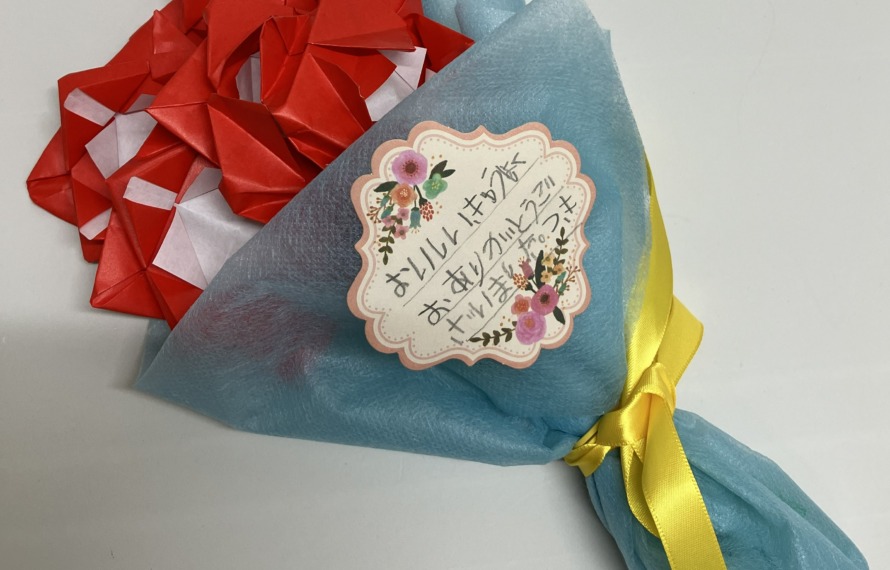 「おいしいきゅうしょくありがとうございました。つき」のメッセージ付きの折り紙の花束の写真