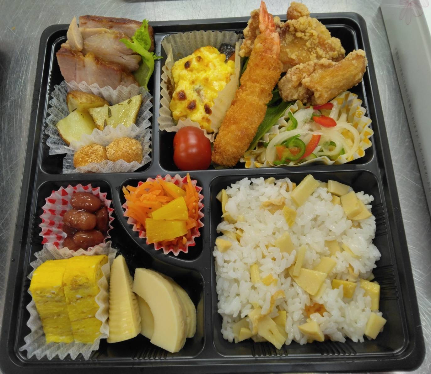 特別弁当（筍ご飯、鶏の塩から揚げ、エビフライ、イカのマリネ、鮭のコーンマヨネーズ焼き、ミニトマト、豚肉のチャーシュー、ローズマリーポテト、白玉団子、人参パインサラダ、若竹煮、玉子焼き、煮豆）の写真
