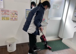 ワーカーがマットの上を掃除機かけしている