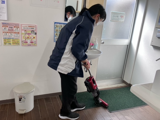 ワーカーがマットの上を掃除機かけしている