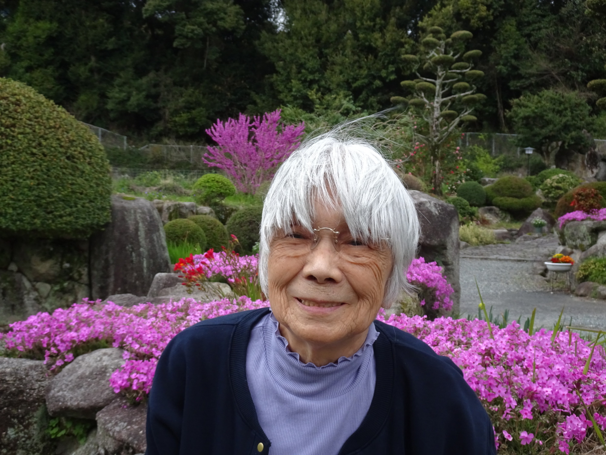 ピンクの花の前で撮った利用者さんの写真