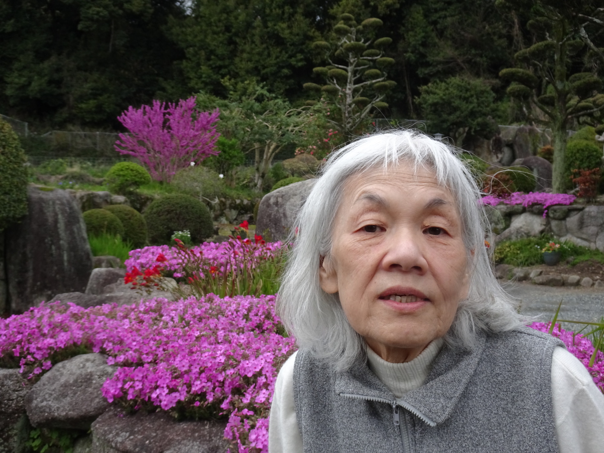 ピンクの花の前で撮った利用者さんの写真