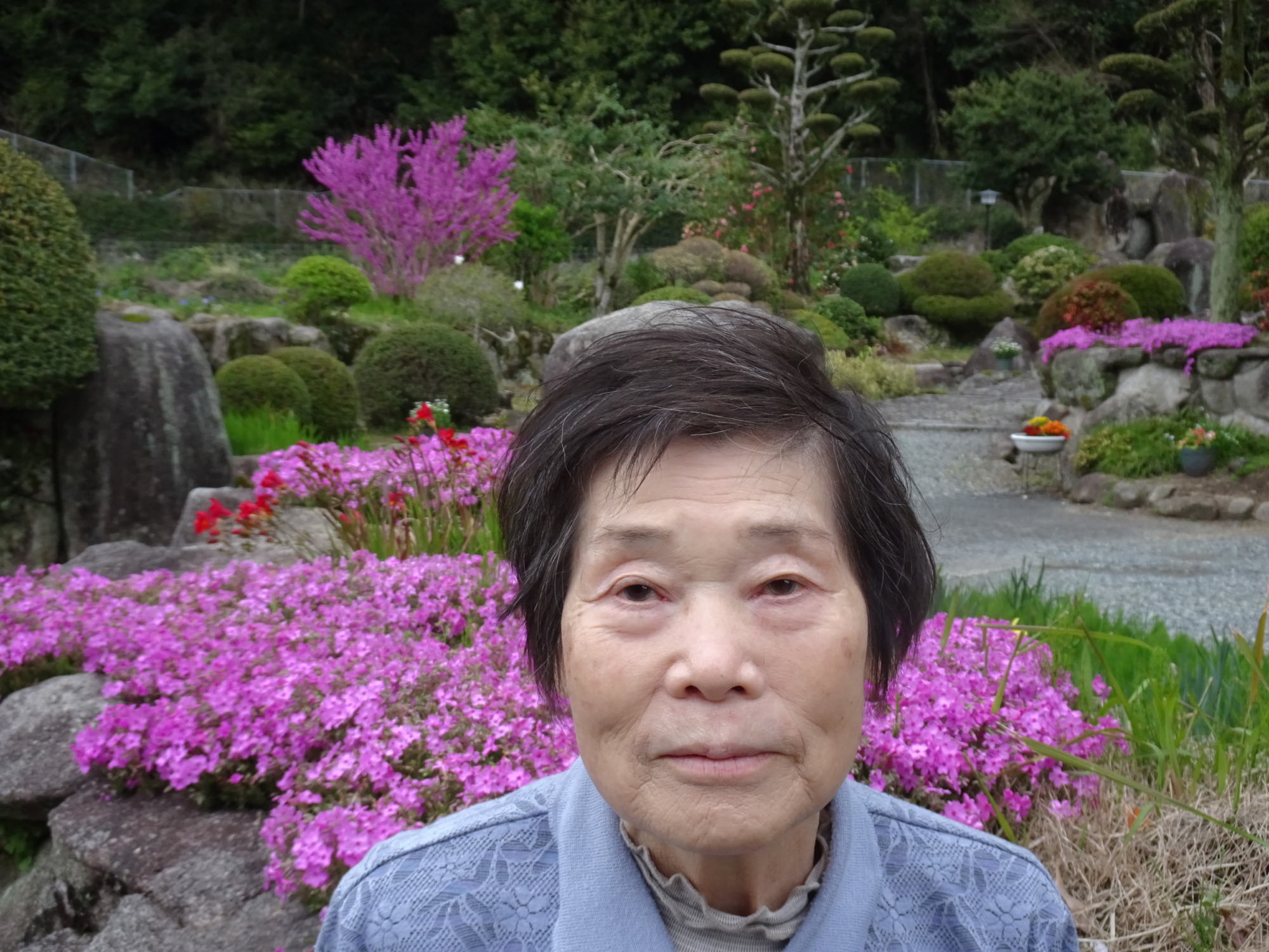 ピンクの花の前で撮った利用者さんの写真