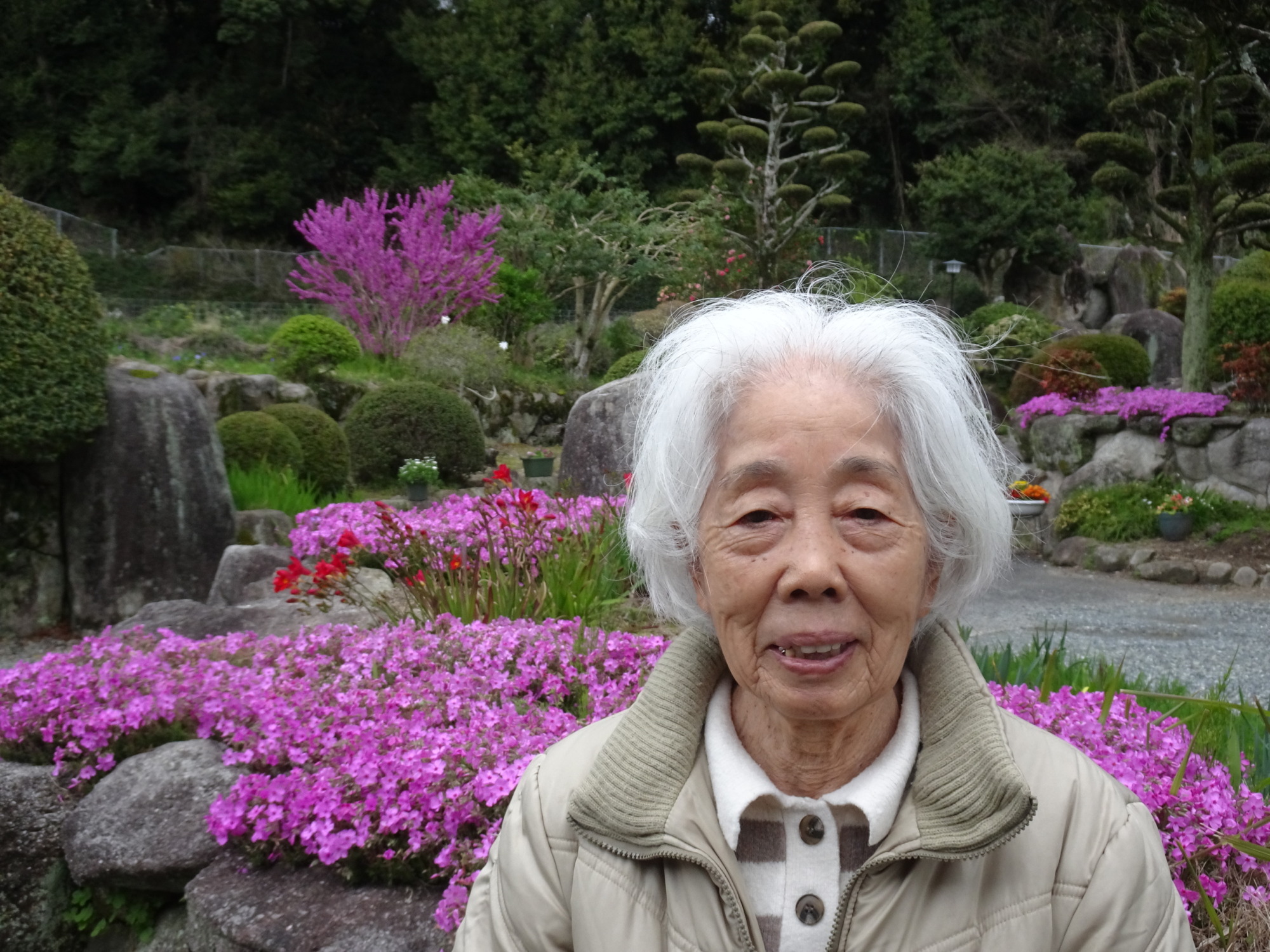 ピンクの花の前で撮った利用者さんの写真