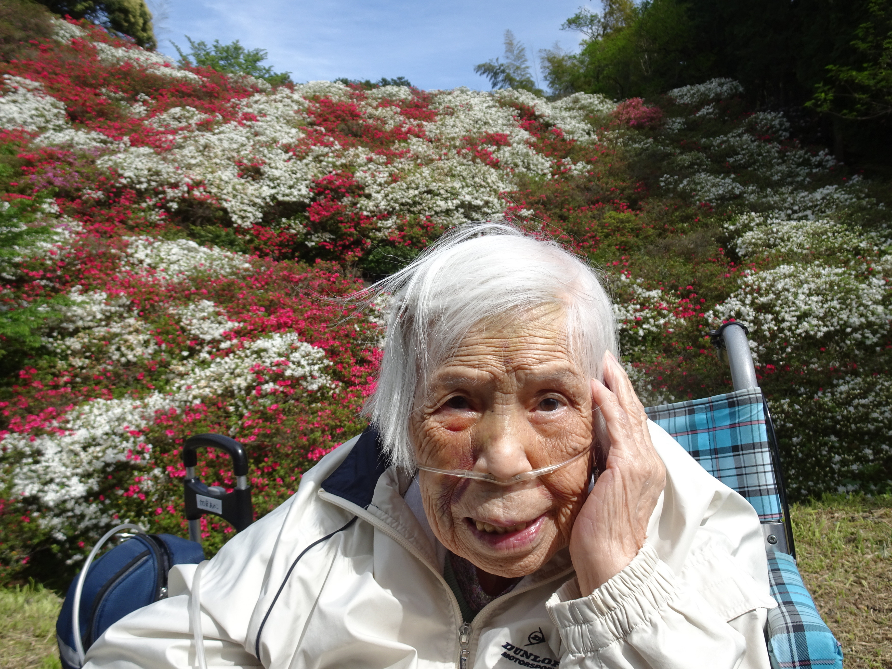 赤白ピンクのツツジがたくさん咲いてる前で撮った利用者さんの写真