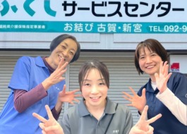 事業所に戻ってきたワーカーが真ん中で笑顔でピースサイン。両脇にサービス提供責任者2人が笑顔で見守っている