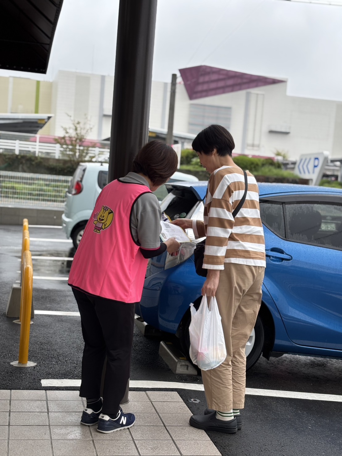 グリーンコープ福津店の入口でワーカーがお客様にアンケートを渡している