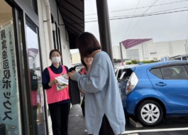 グリーンコープ福津店の入り口でお客様にワーカーがアンケートを渡している