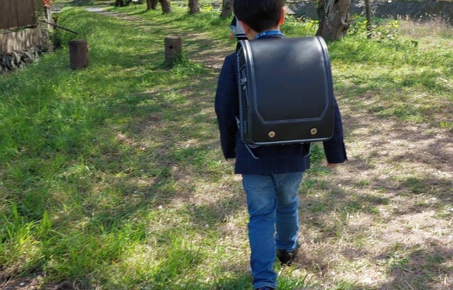 ワーカーの子どもがランドセルを背負って歩いている後ろ姿