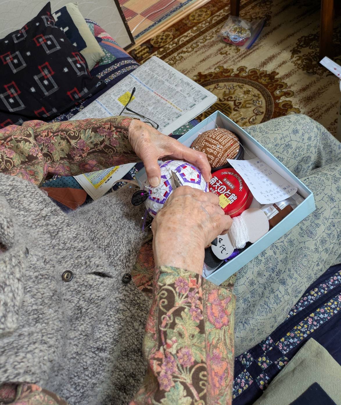 ソファーに座って手鞠を作られ、手鞠の糸を切ってある利用者様