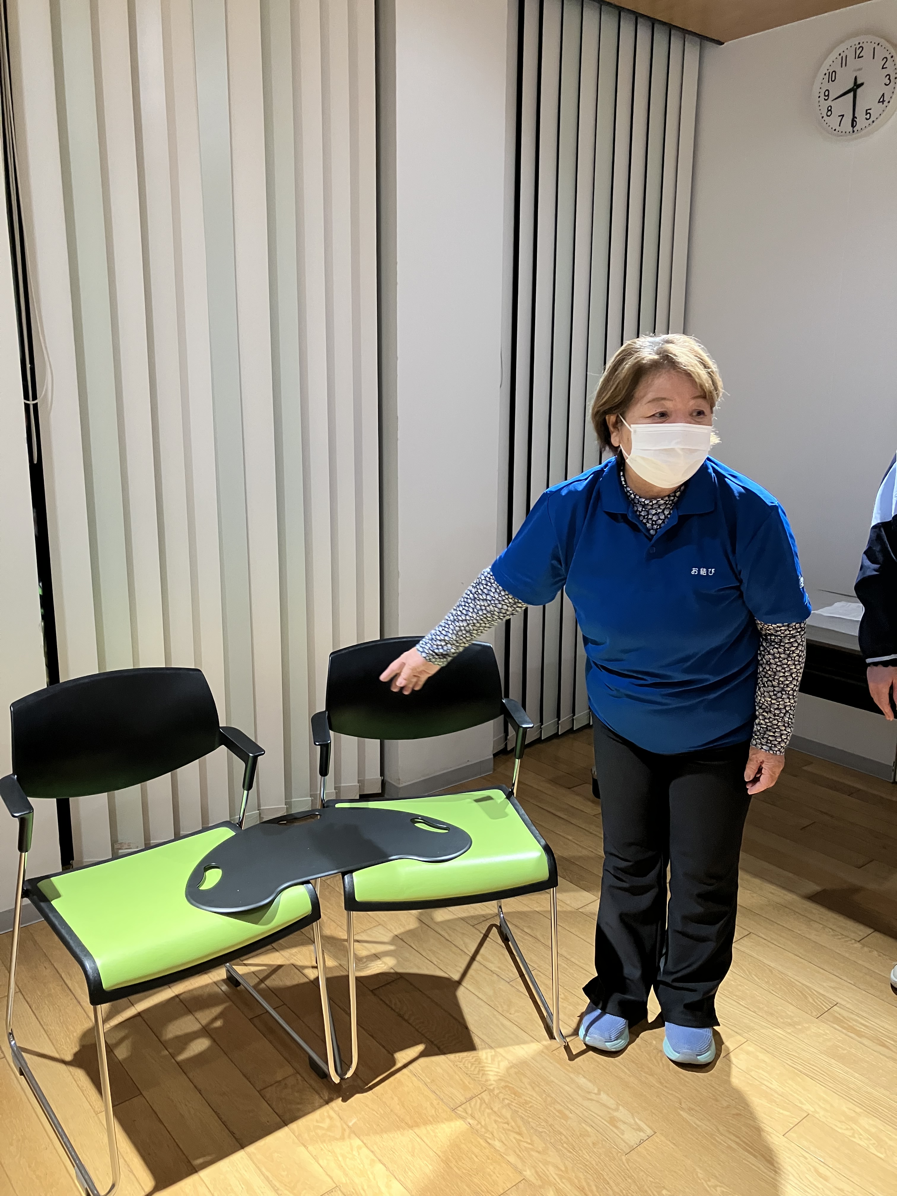 職場会議でワーカーが二脚の椅子間にバイキングボードを置いて説明をしている。