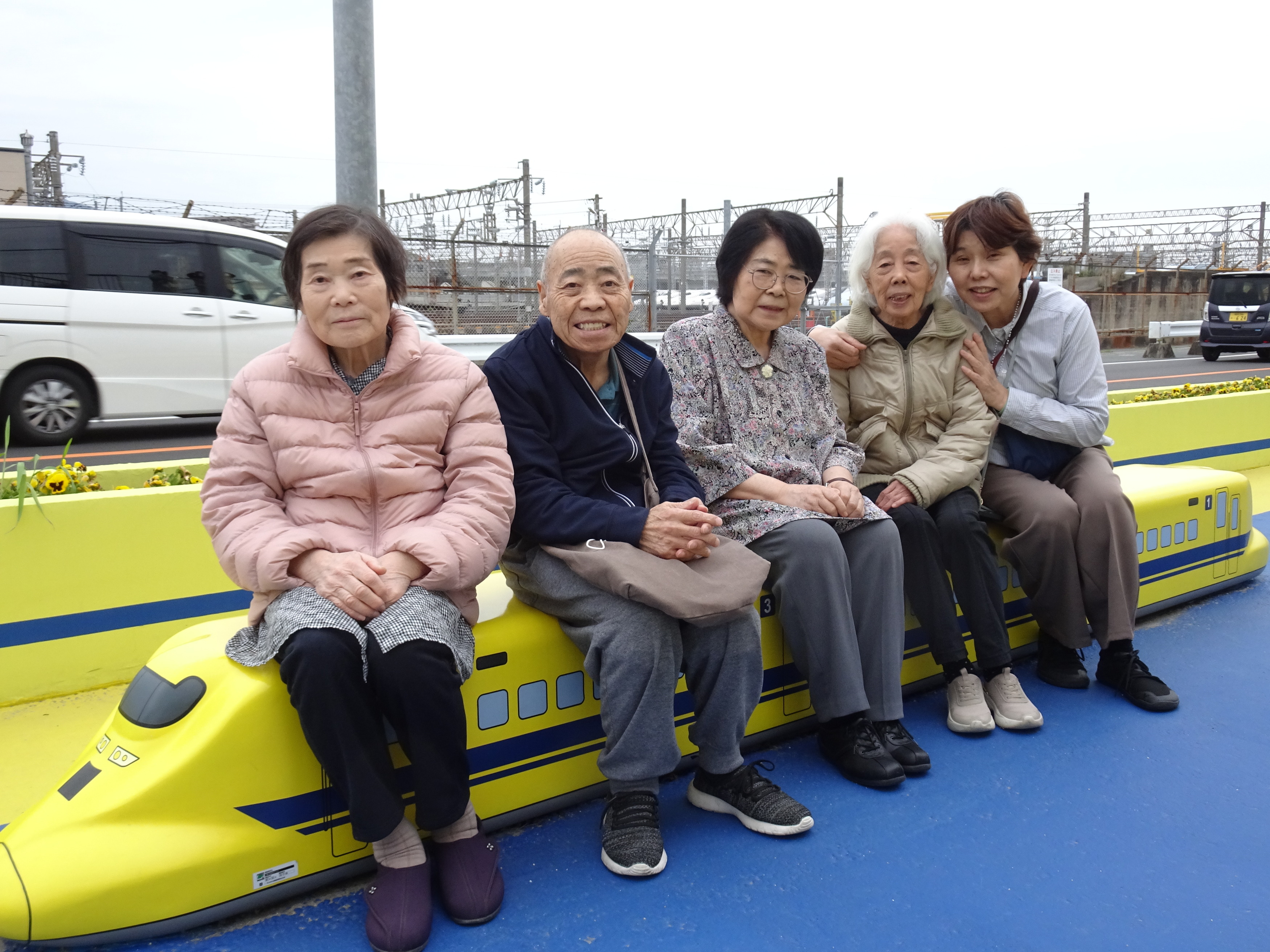 ドクターイエローを模したベンチに座る利用者さんたちとワーカー