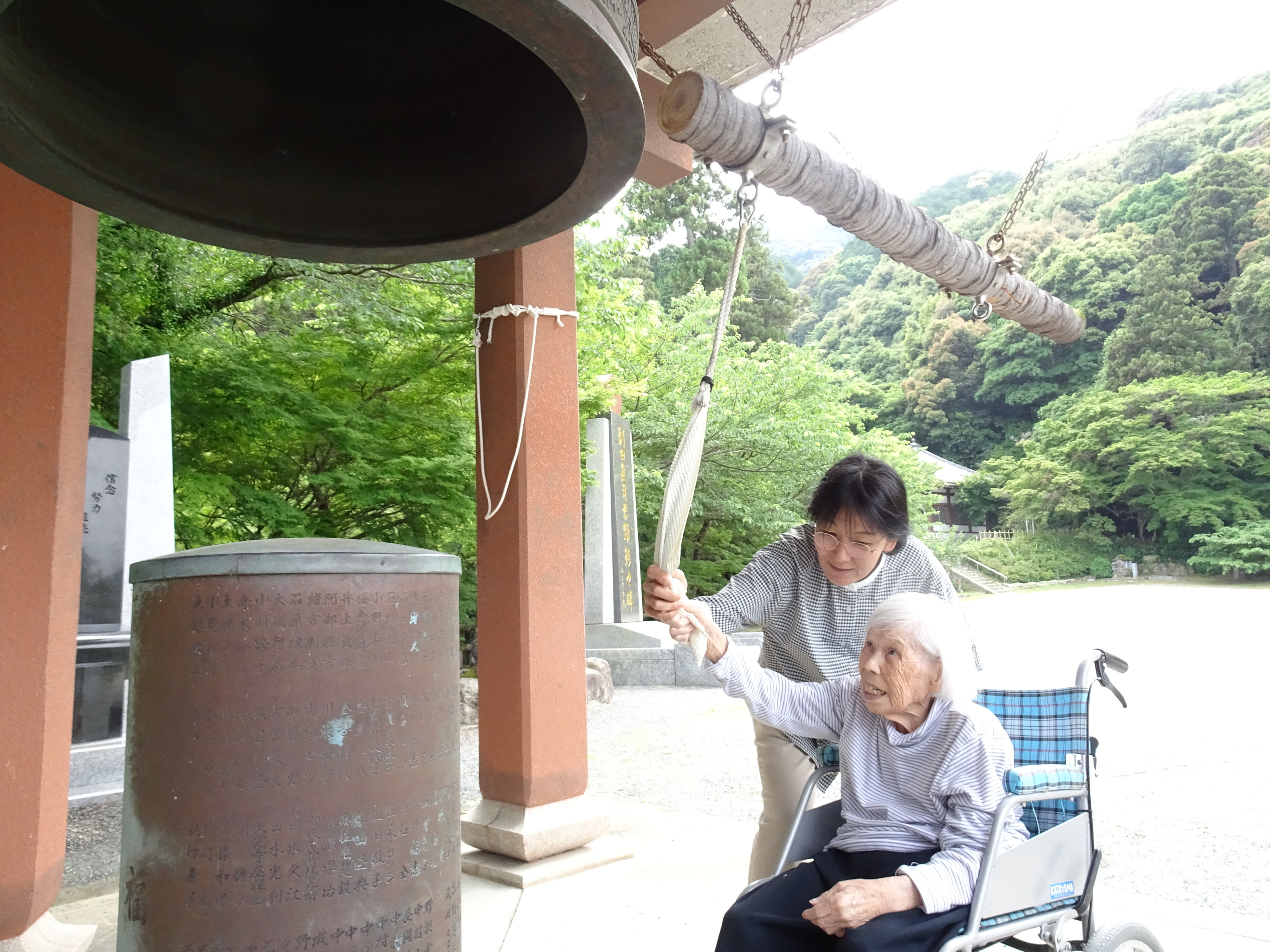 ワーカーと一緒に幸福の鐘をつく利用者さん