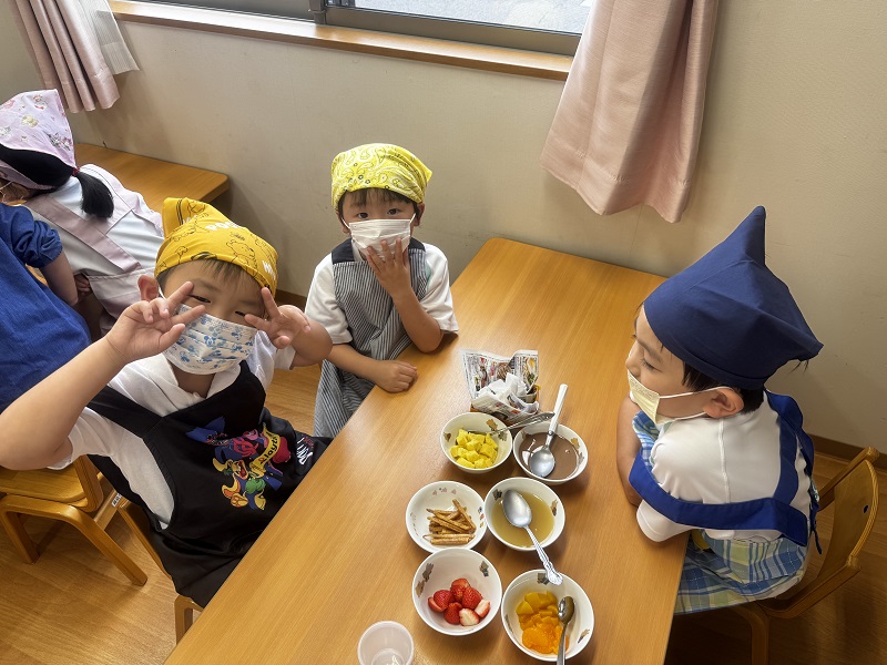 パフェ作りの材料を前にポーズを決める子ども