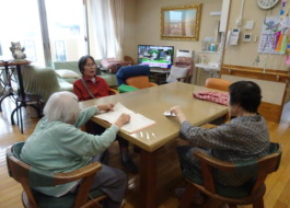 グループホームでの日常の様子 テーブルで3人の利用者さんが集っているところ