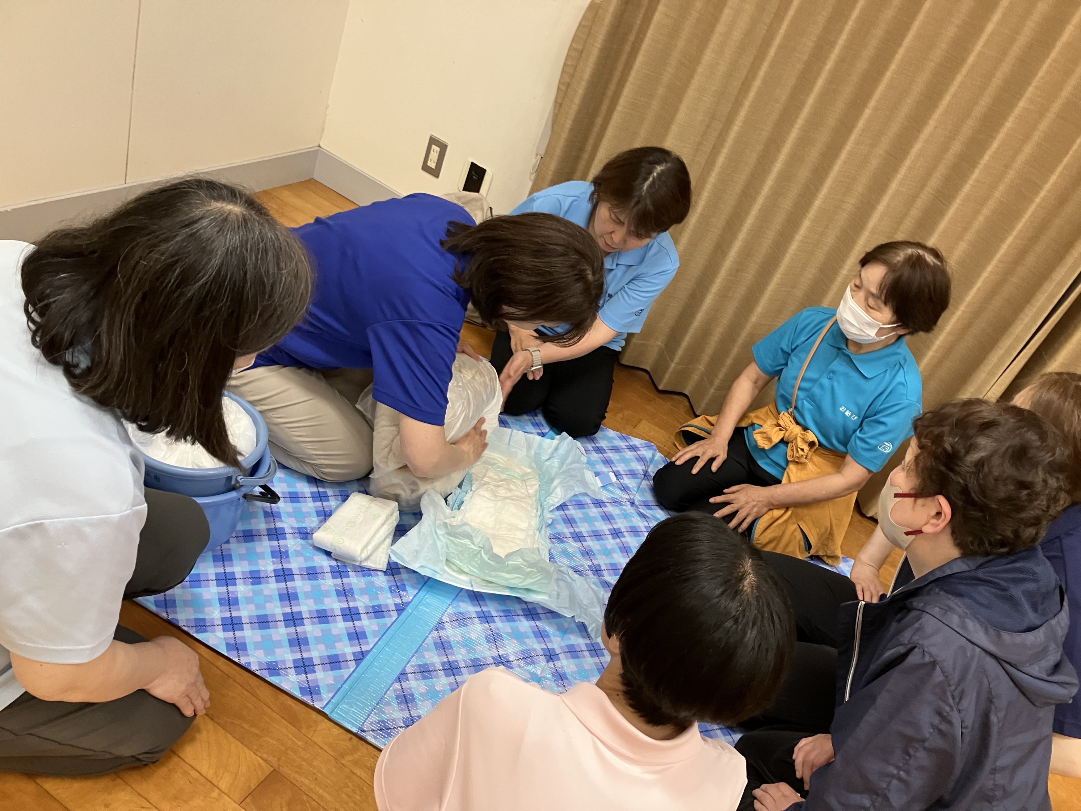 職場会議でワーカーが集まりおむつ交換時の泡洗浄のやり方を確認している