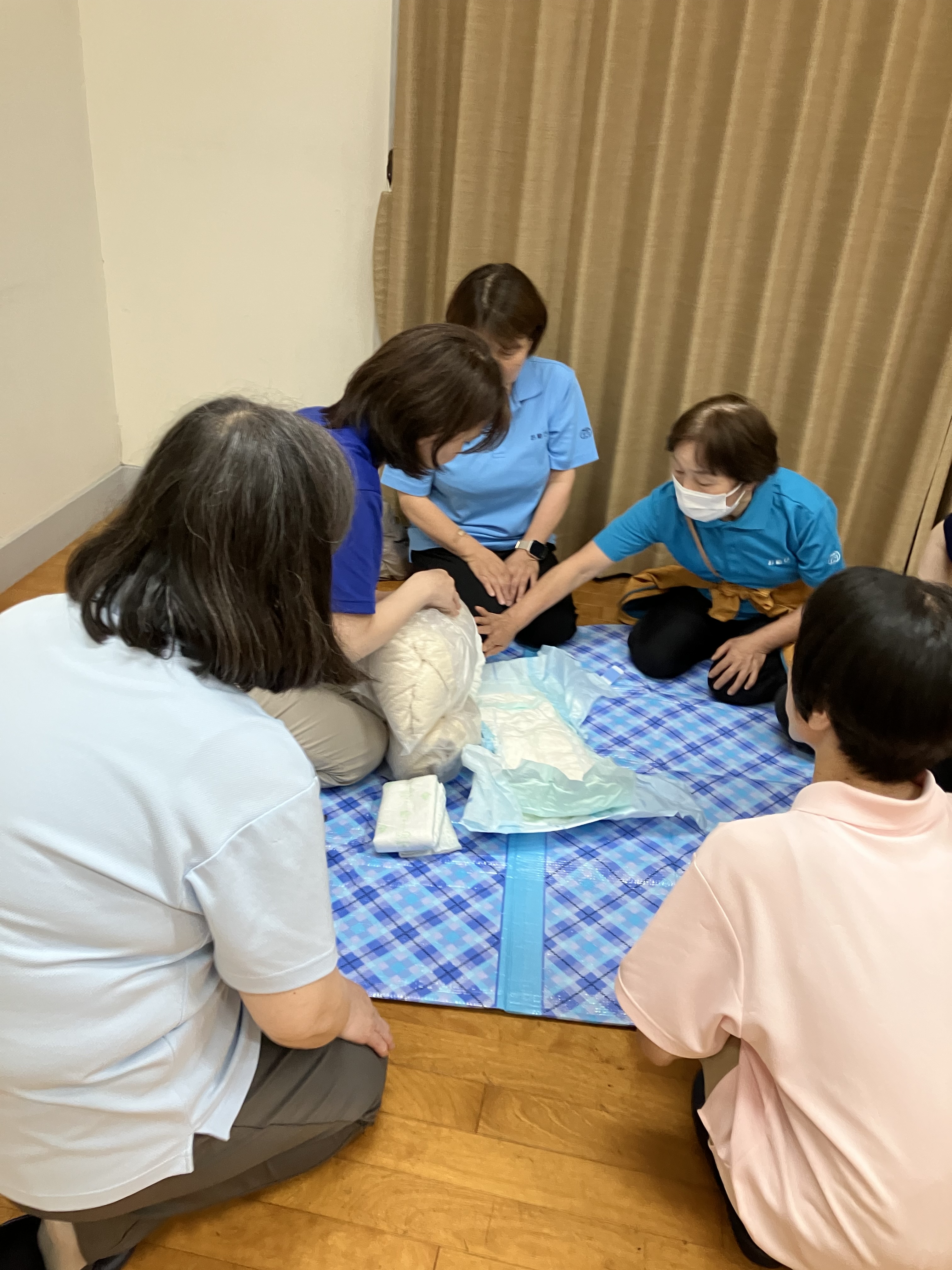 職場会議でワーカーが集まりおむつ交換時の泡洗浄のやり方を確認している