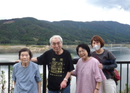 ダムの前で写る利用者さんたちとワーカー