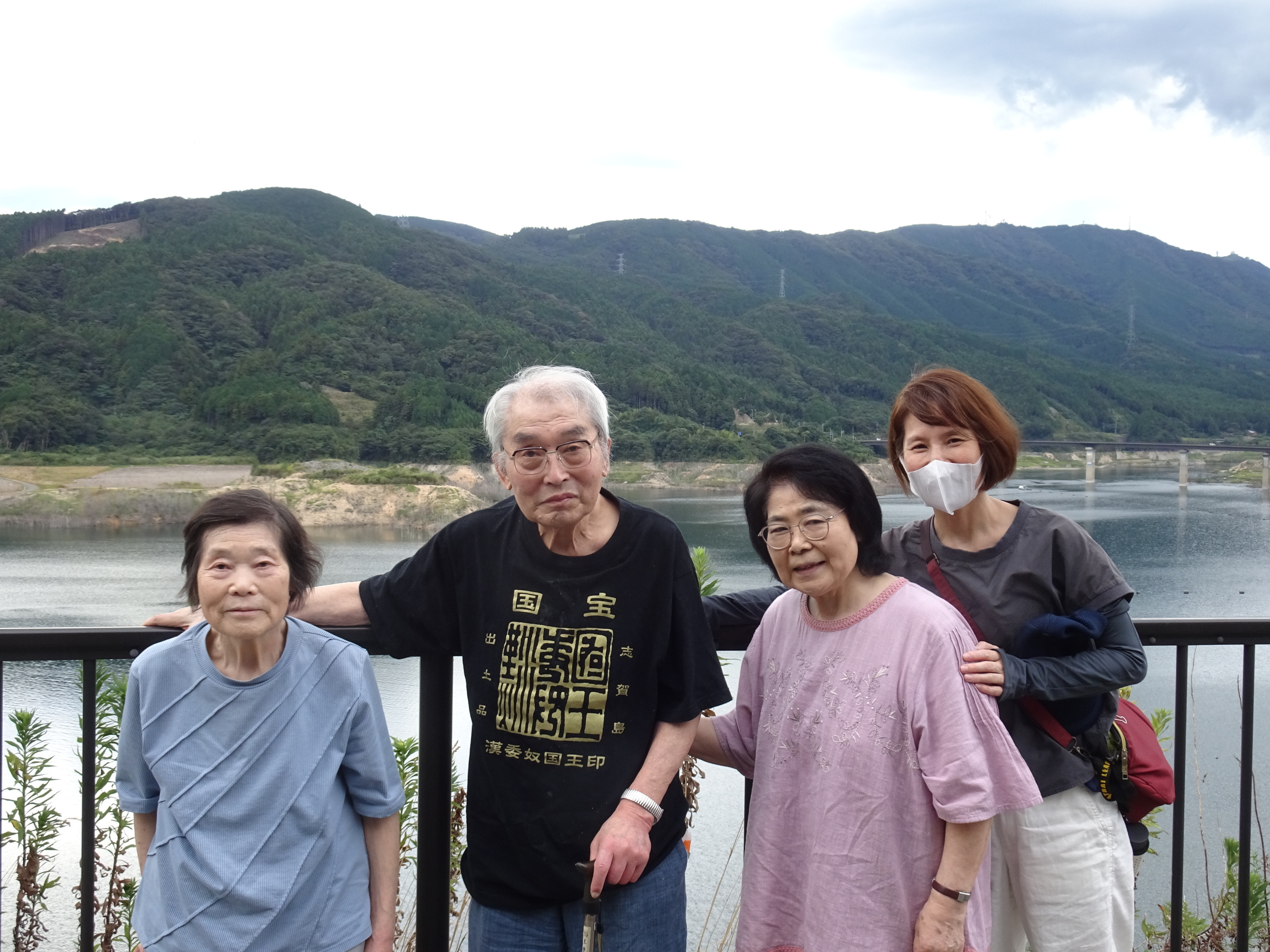 ダムの前で写る利用者さんたちとワーカー