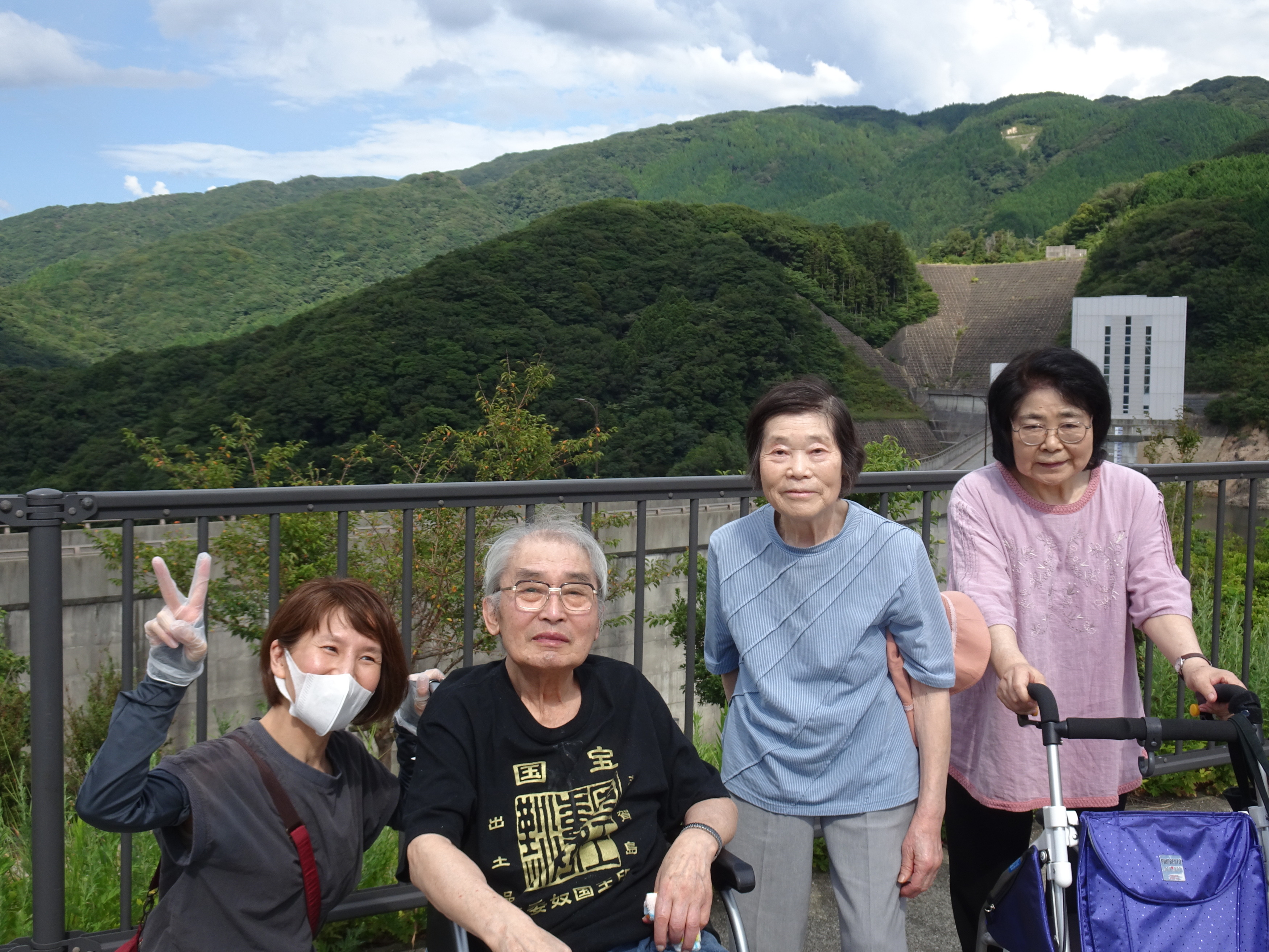 ダムの前で写る利用者さんたちとワーカー