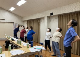 職場会議でみんな立って腰をそらして腰痛体操をしている