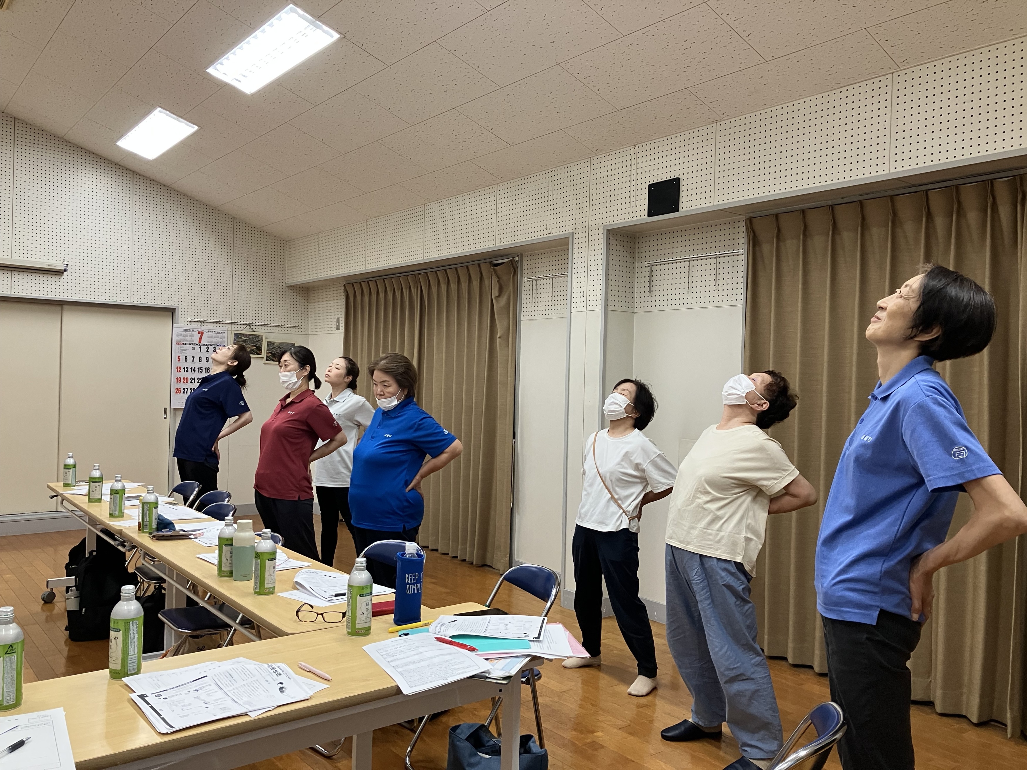 職場会議でみんな立って腰をそらして腰痛予防体操をしている