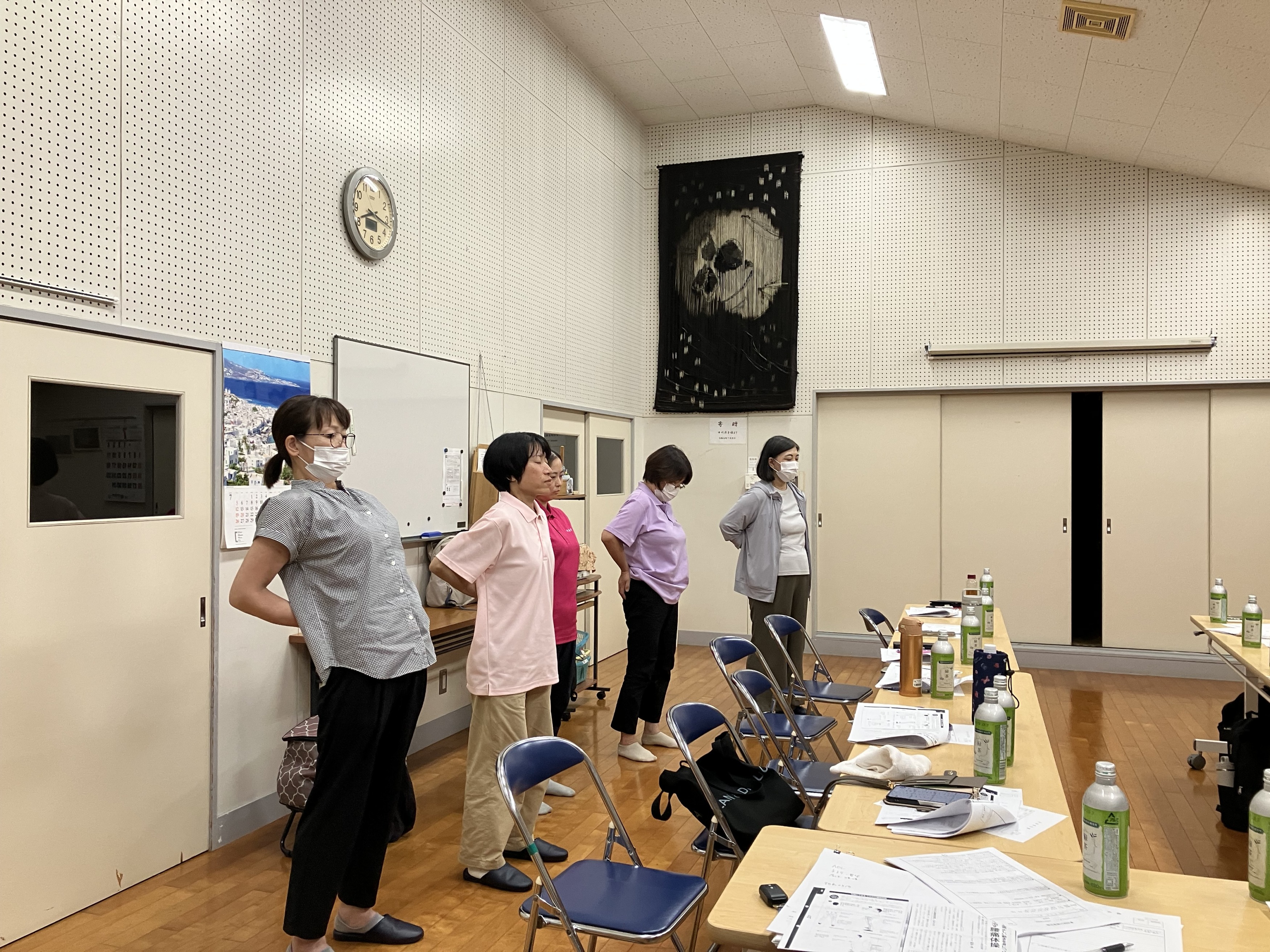 職場会議でみんな立って腰をそらして腰痛予防体操をしている