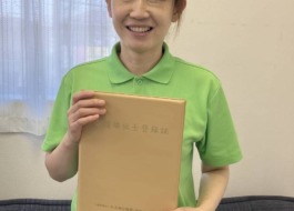ワーカーが介護福祉士国家試験に合格し、介護福祉士資格証を手に持ち微笑んでいる