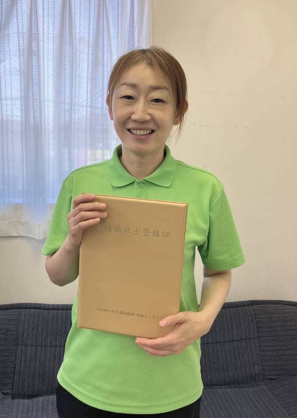 ワーカーが介護福祉士国家試験に合格し、介護福祉士資格証を手に持ち微笑んでいる