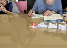 折り紙の本を見ながら折り始める利用者さん