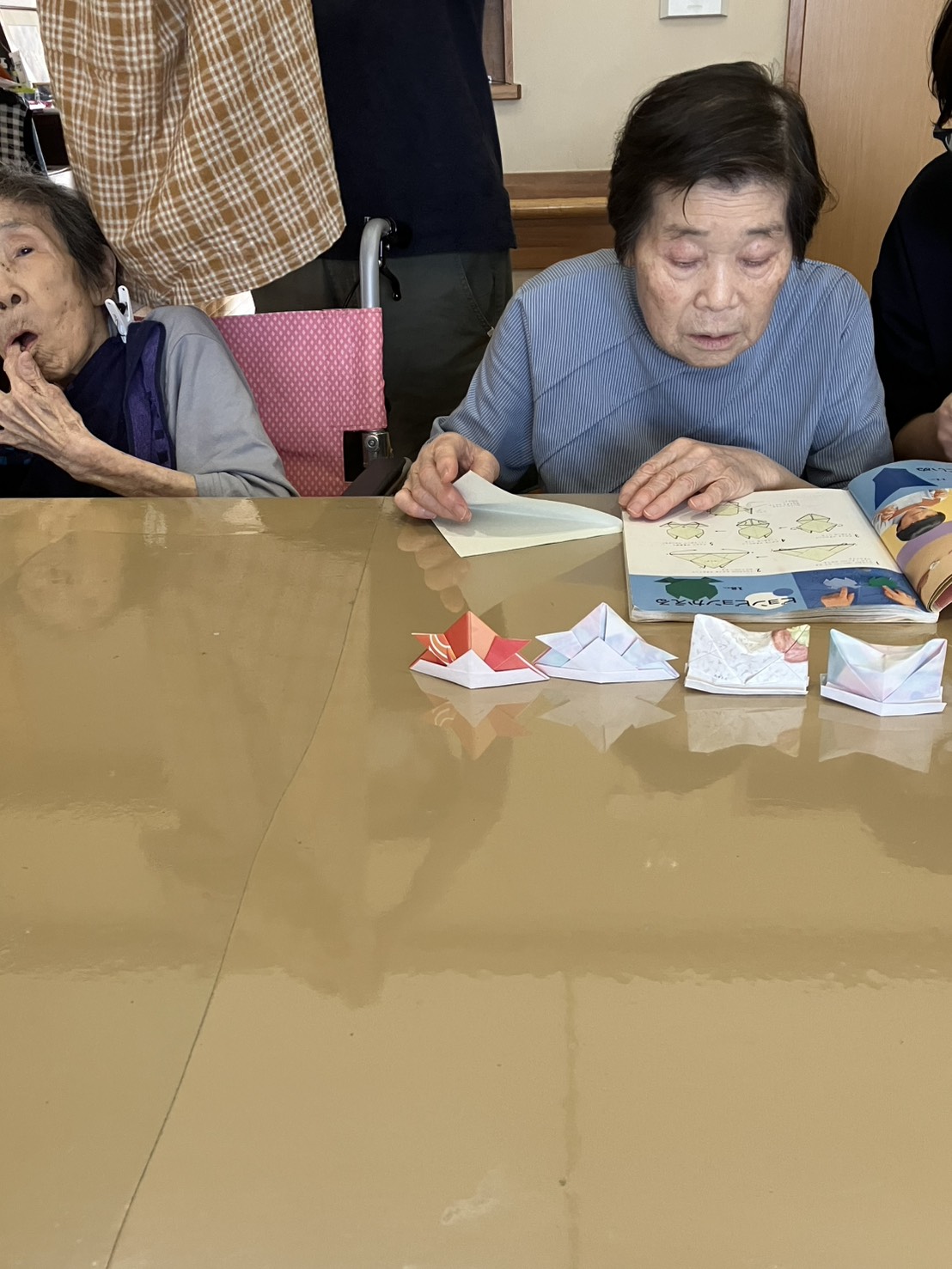 折り紙の本を見ながら折り始める利用者さん