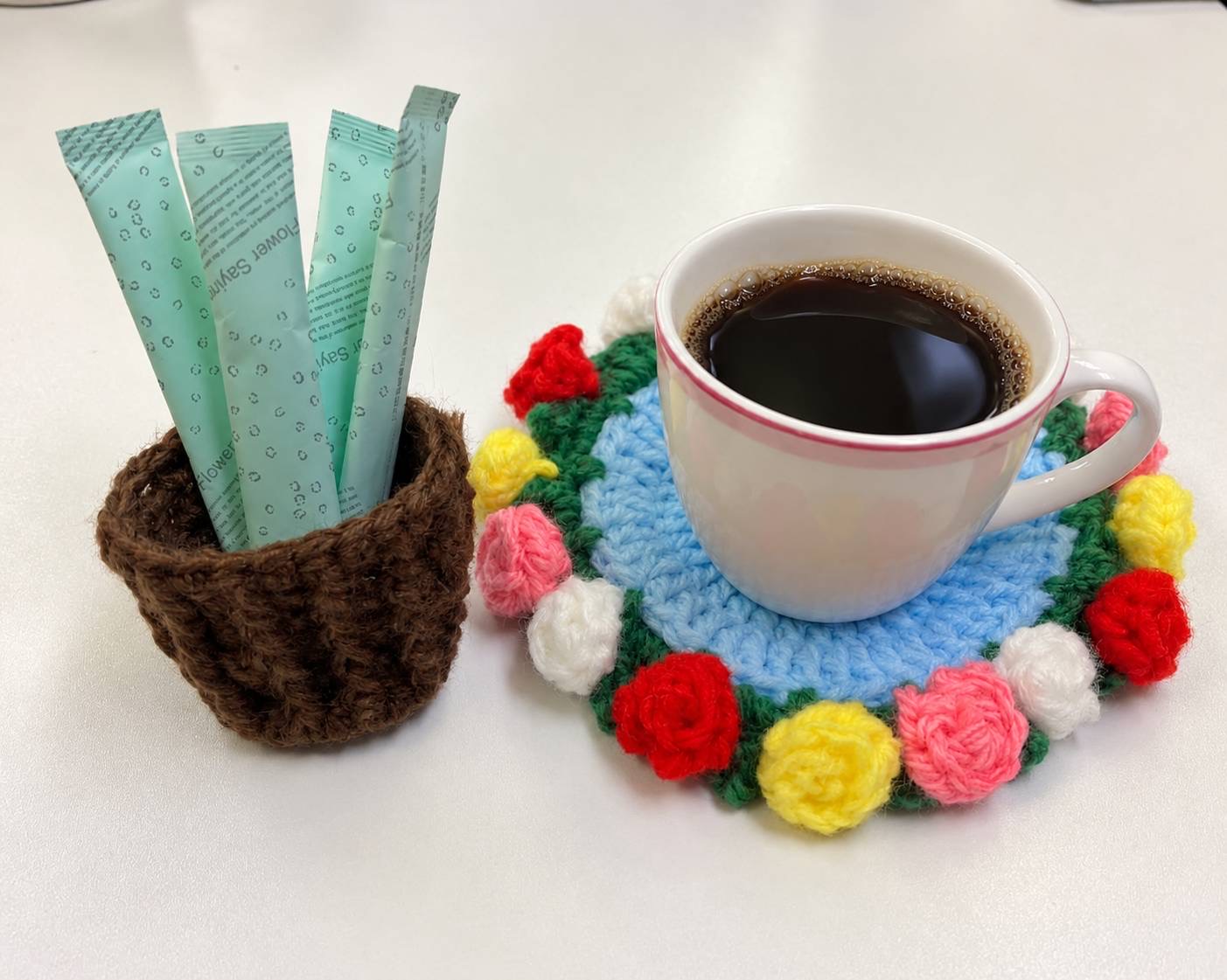 利用者様のお母様が編んで作られたコースターにコーヒーカップ、小物入れに砂糖が入っている