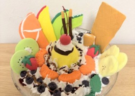 小学4年生の利用者様が粘土で作られたパフェ。真ん中にプリン周りにフルーツやホイップクリーム、ポッキーなどが飾られている