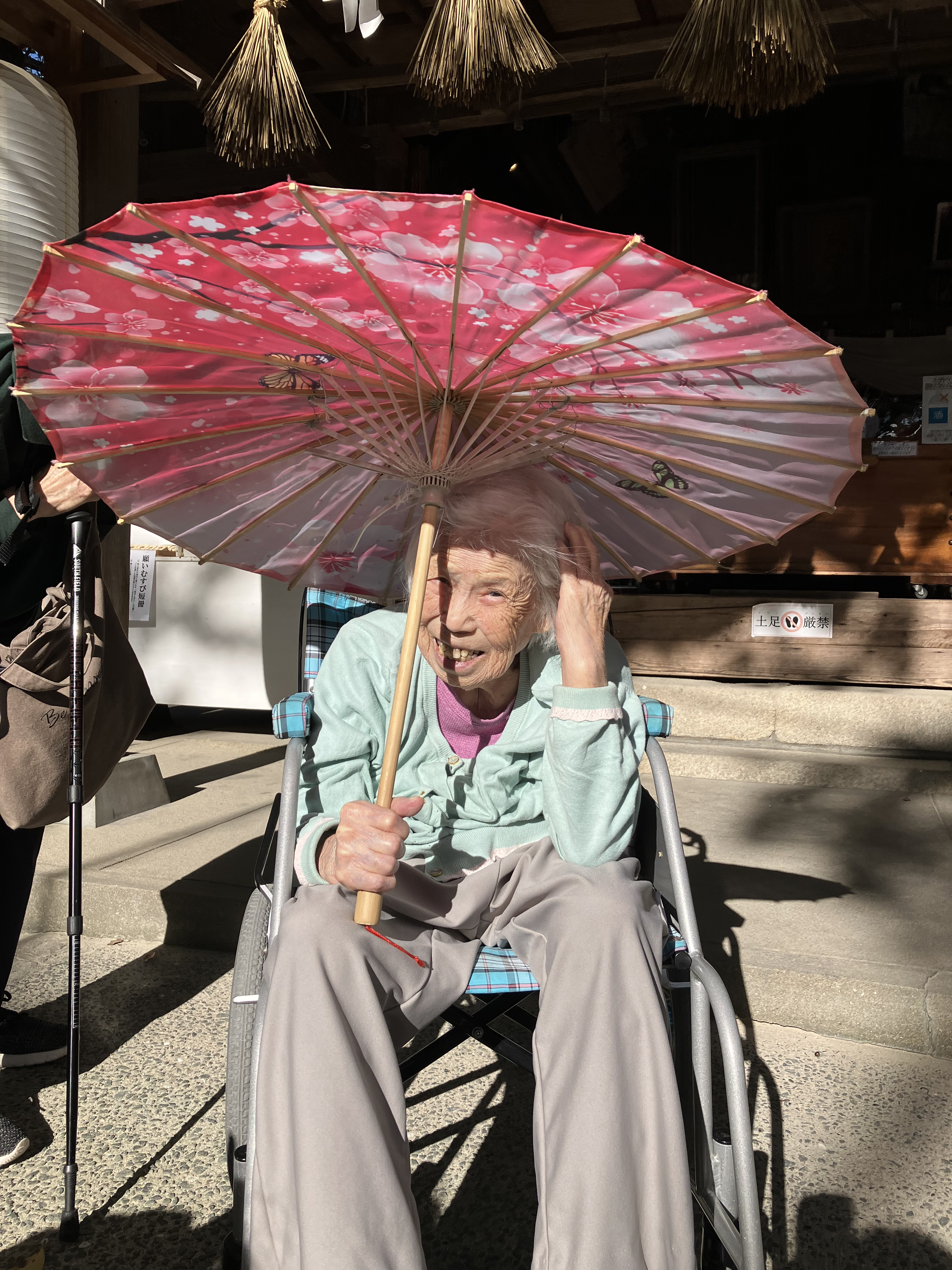 赤色の和傘をもってポーズをとる利用者さん