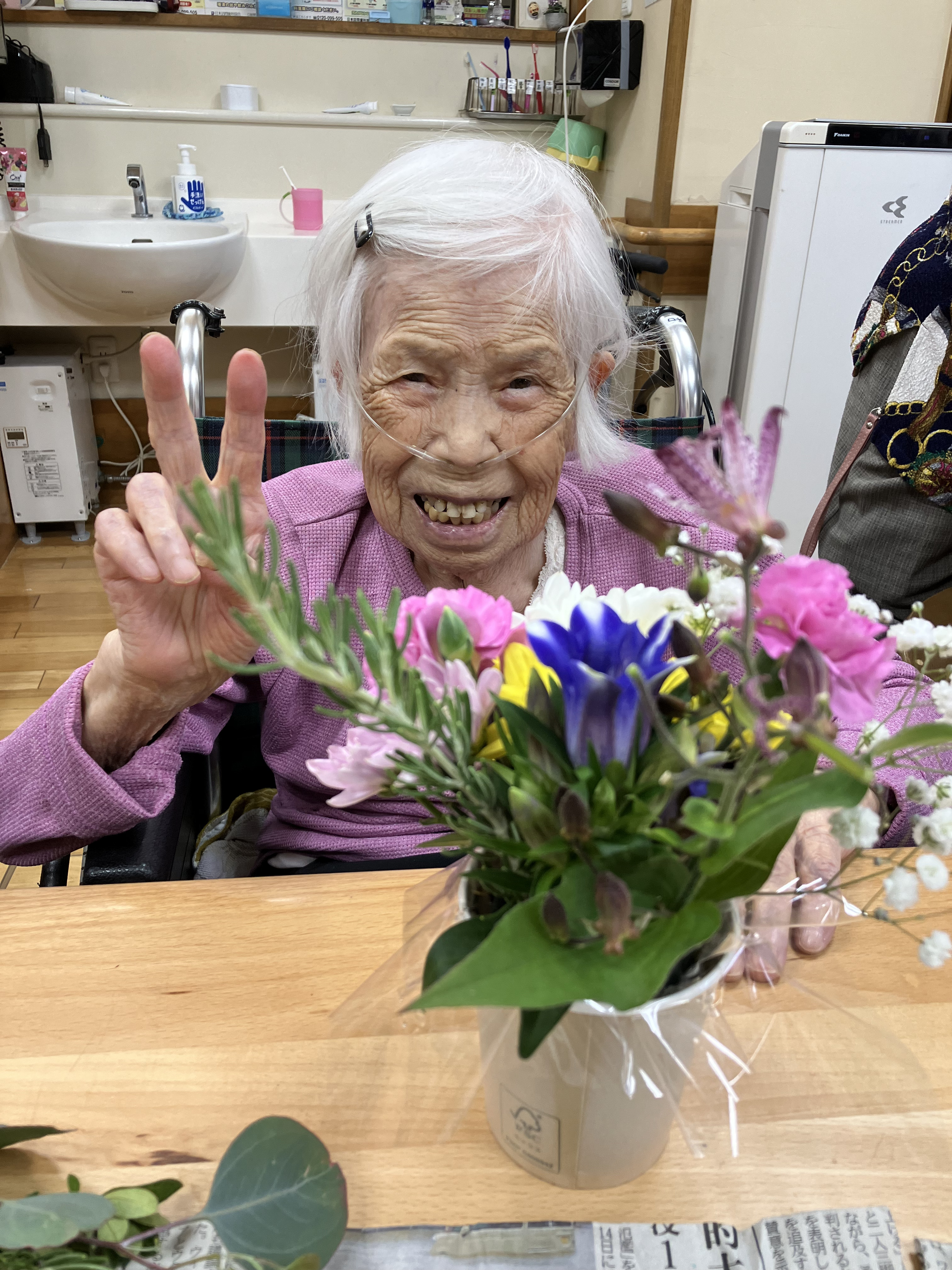 完成したフラワーアレンジメントと一緒にうつる利用者さん